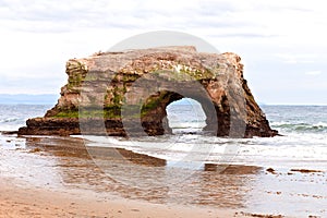 Large Rock Formation With Tunnel on a Sandy Beach in Santa Cruz, California, USA photo