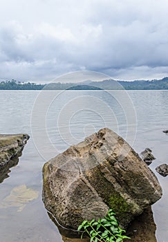 Large rock laying in peaceful Barombi Mbo crater lake in Cameroon, Africa photo