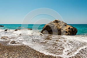 A large rock surrounded by water at Pissouri pebble beach, Cyprus