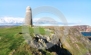 A large rock tower sits near a coastal cliff in Scotland