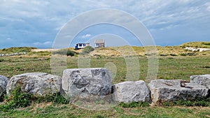 Large rock wall in field with house in background