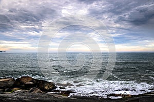 Large rocks, many clouds, and the horizon on a seascape