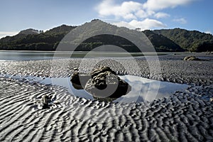 Large rocks in pool of water with cloud reflection at North Taranaki, New Plymouth