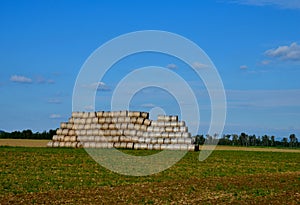 a large roll of baled straw is stacked in a pyramid. warn friends not to