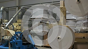 A large roll of cellulose, a material made of natural wood, rotates slowly on the machine. The beginning of the