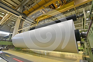 Large roll of paper on a crane in a mill for the production of p