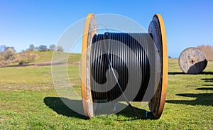 A large roll of wood with a black cable lies in the landscape.