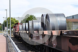 Large rolls of sheet metal lying on a freight wagon pulled by locomotives.