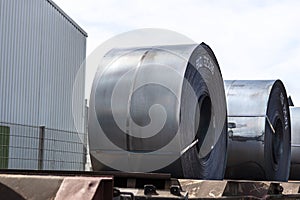 Large rolls of sheet metal lying on a freight wagon pulled by locomotives.