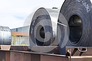 Large rolls of sheet metal lying on a freight wagon pulled by locomotives.