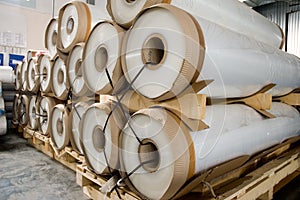 Large rolls of transparent polyethylene lie on a pallet.