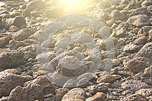 Large round stones boulders lie on the beach, on the sea, against the background of the sun
