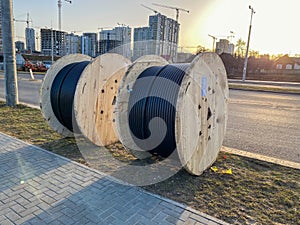 Large round wooden spools of bobbins with wires, black electric cables in rubber insulation, used in the wiring of conductor lines