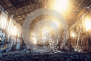 Large ruined and demolished abandoned factory hangar or warehouse in sunlight, post apocalyptic disaster concept