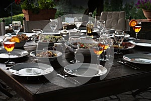 Large rustic table prepared with mediterranean salads and antipasti for a garden dinner at night