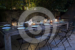 Large rustic table prepared for a outside dinner at night