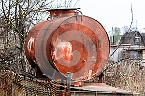 A large rusty metal container for water at the dacha