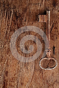 Large rusty vintage metal key on old wooden background