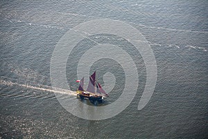 A large sailboat goes to sea under sail. View from above.