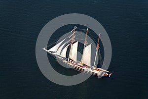 A large sailboat goes to sea under sail. View from above.