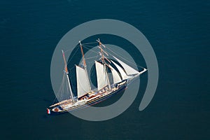 A large sailboat goes to sea under sail. View from above.