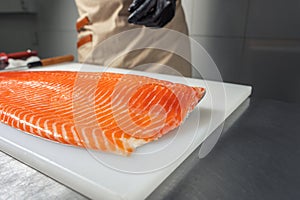 A large salmon awl on a white chopping Board