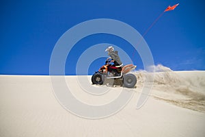 Large sand spray from ATV quadbike rider in the du