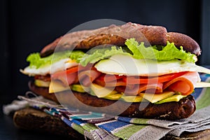 Large sandwich with avocado ham chese and egg, dark background