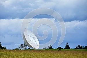 Large satellite dish in the field for receiving and transmitting tv signal and data transfer to the satellite, teleport