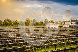 Large scale solar farm with the satellite dishes under dramatic