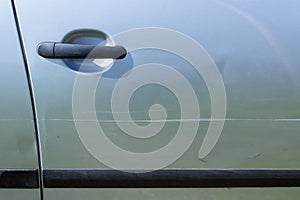 A large scratch on the door of a silver car.