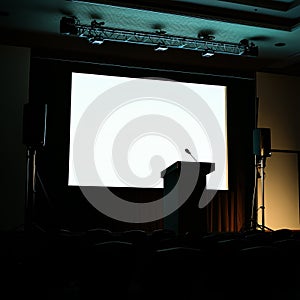 A large screen is lit up with a microphone on a podium