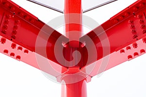 Large screw hexagon flange red nut supporting structures, metal frame of prefabricated building on white background.