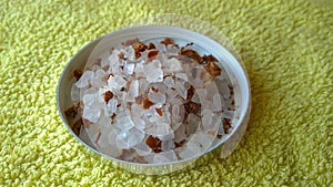 Large sea bath salt in a small box with flower petals on the towel