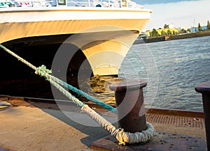 Large sea ship mooring bollard on dock with anchor ropes attached