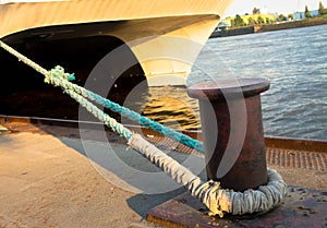 Large sea ship mooring bollard on dock with anchor ropes attached