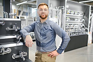 A large selection of water faucets. Man chooses a products in a sanitary ware store