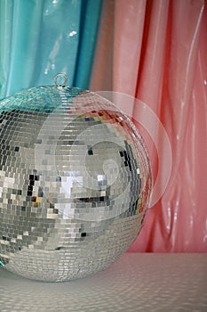 Large shiny reflective mirror silver sparkling nightlife disco ball against color background