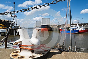 Large ship for transporting aggregates in Whitstable harbour. There is a large mooring bollard in the foreground in softer focus