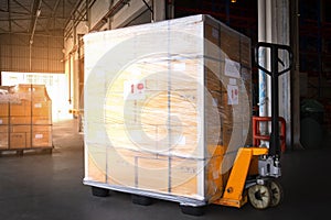 Large shipment pallet goods and hand pallet truck at interior warehouse storage