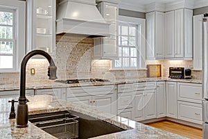 Large Sink with Faucet and Luxury Kitchen Interior with Stone Backsplash in Background