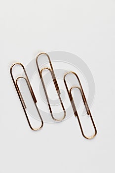 large sized copper paper clips lie on white blank paper