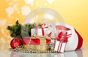 Large and small boxes in the header of Santa Claus, next to gift in heart shaped decorations for the Christmas tree, on yellow