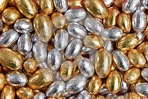 Large & small gold and silver foil wrapped chocolate easter eggs for use as a background.