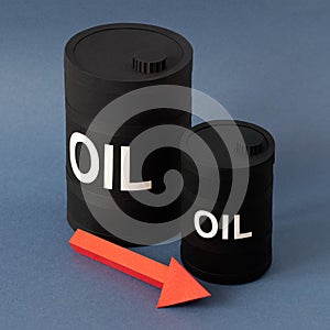 Large and small paper barrels of oil with arrow showing decrease