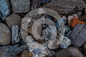 Large and small rough broken colorful texture stones with glass on shore of lake