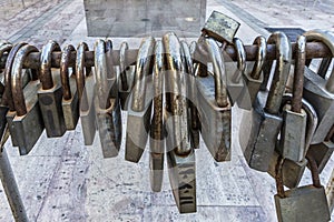 Large and small rusty padlocks on a metal railing