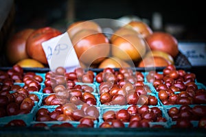 Large and small tomatoes for sale in green baskets
