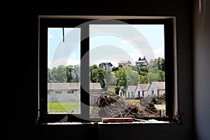 Large and small windows with broken at abandoned house overlooking piles of cut down trees and military complex hangars