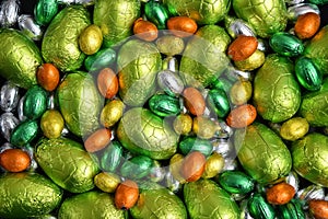 Large & small yellow, gold, orange, green and silver spring colours of foil wrapped chocolate easter eggs.